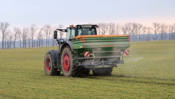 Ein Traktor bringt Düngung auf dem Feld aus